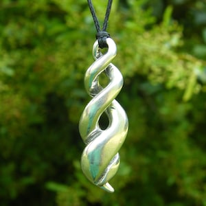 Può includere: Una collana con un ciondolo d'argento con un design a spirale intrecciato. Il ciondolo è appeso a un cordoncino nero.