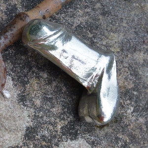 Könnte beinhalten: Eine silberfarbene Metallsculptur eines menschlichen Körperteils. Die Skulptur ist glatt und glänzend, mit einer realistischen Form.