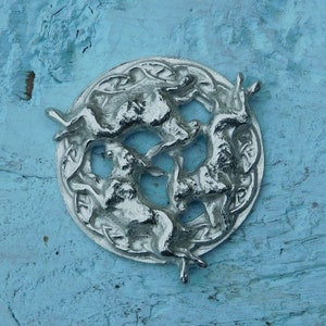 May include: A silver-coloured metal pendant featuring three hares in a circle, a traditional Celtic design.