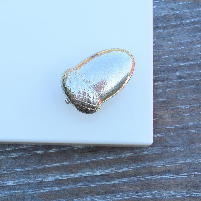May include: A silver acorn shaped door knob with a detailed design.