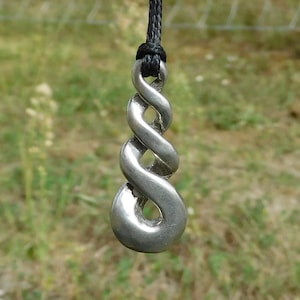 May include: A silver pendant with a twisted knot design hangs from a black cord. The pendant is a traditional Celtic knot, symbolising eternity and interconnectedness.