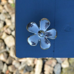 May include: A silver flower-shaped door knob with five petals.