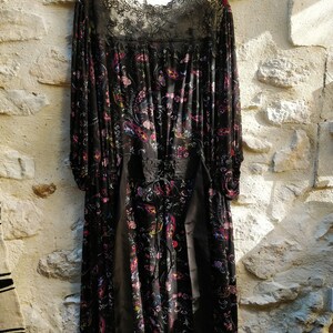 Puede incluir: Un vestido maxi negro con estampado floral y escote de encaje. El vestido tiene mangas largas y un corpi&ntilde;o ajustado.