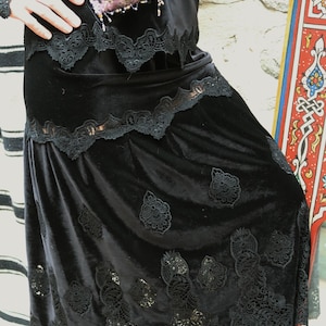 May include: A black velvet skirt with a lace overlay. The skirt has a scalloped hem and a floral design.