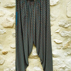 May include: Black and green patterned pants with a geometric design. The pants have a wide leg and a loose fit.