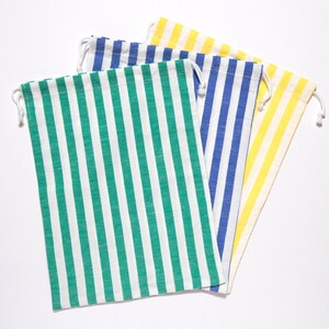 Puede incluir: Cuatro bolsas de tela a rayas con cordón. Las bolsas son verde, azul, amarilla y blanca.