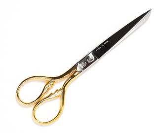 May include: Gold-handled scissors with a silver blade. The blade is marked "Acier de Spain".