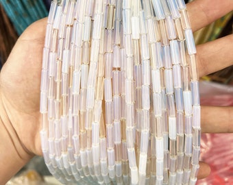 May include: A strand of iridescent white glass beads, each bead is a rectangular tube shape.