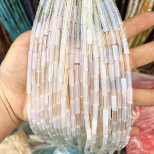 May include: A strand of iridescent white glass beads, each bead is a rectangular tube shape.