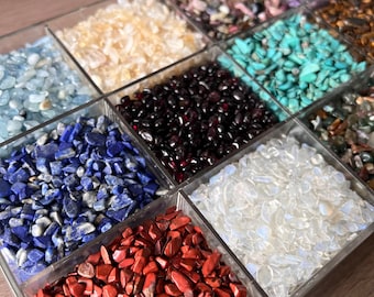 May include: A clear plastic tray with ten compartments filled with various types of small, colorful gemstones. The gemstones are arranged in rows and include aquamarine, amethyst, lapis lazuli, red jasper, clear quartz, and more.