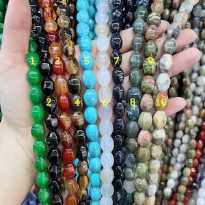 May include: Ten strands of gemstone beads, each strand is a different color and pattern. The beads are oval shaped and have a smooth, polished finish. The strands are numbered 1 through 10.