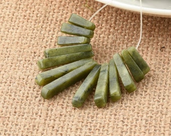 May include: A strand of green jade gemstone beads, each bead is a long, thin, and slightly tapered rectangle. The beads are strung on a clear elastic cord.