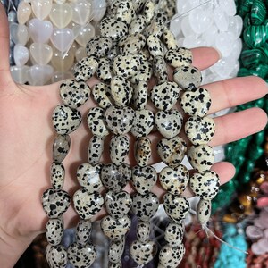 May include: A strand of heart-shaped dalmatian jasper beads. The beads are a light brown color with black spots.
