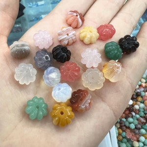 May include: Assortment of 18 flower-shaped gemstone beads in various colors, including pink, green, white, brown, and black. The beads are carved from natural stone and have a smooth, polished finish.