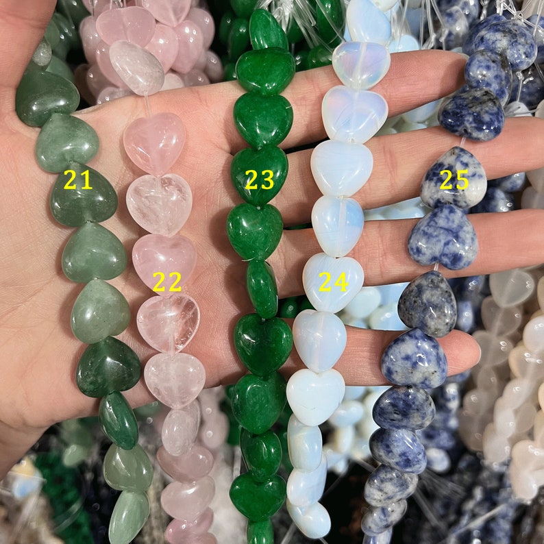 May include: Four strands of heart-shaped gemstone beads. The strands are labeled 21, 22, 23, and 24. The beads are green, pink, white, and blue.
