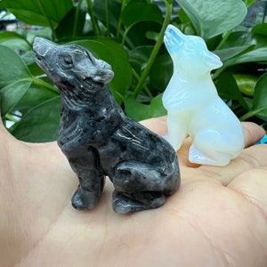 Könnte beinhalten: Zwei geschnitzte Wolfsfiguren, eine schwarz und eine weiß, aus poliertem Stein. Die Wölfe sitzen aufrecht mit nach oben geneigten Köpfen.