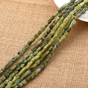 Könnte beinhalten: Eine Strähne grüner Jade-Quadratperlen. Die Perlen sind glatt und poliert, mit natürlichen Farbabweichungen und Mustern.