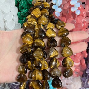May include: A strand of tiger's eye heart-shaped beads. The beads are a mix of golden brown and dark brown colors.