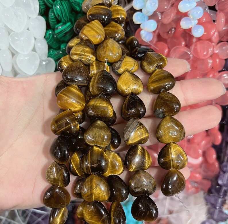 May include: A strand of tiger's eye heart-shaped beads. The beads are a mix of golden brown and dark brown colors.