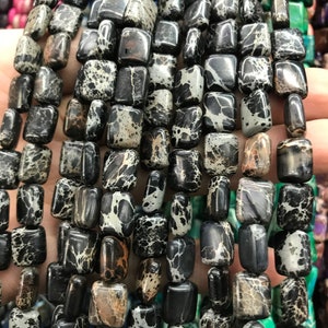 Peut inclure: Un brin de perles carrées tachetées de noir et de blanc. Les perles sont en pierre naturelle et ont une finition polie.