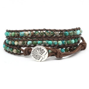 May include: A brown leather wrap bracelet with turquoise and green jasper beads and a silver tree of life charm.