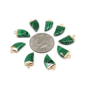 Puede incluir: Diez colgantes de piedra de malaquita verde con bordes chapados en oro y anillos de salto. Los colgantes tienen forma de media luna y están dispuestos en círculo alrededor de una moneda de dólar estadounidense.