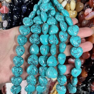 May include: A strand of turquoise heart-shaped beads. The beads are a light blue color with dark blue veining. The beads are strung on a clear elastic cord.