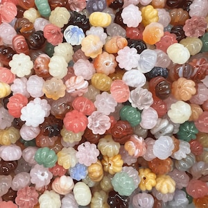 May include: A large assortment of colorful carved gemstone beads in various shapes and sizes. The beads are made of natural stone and have a polished finish.