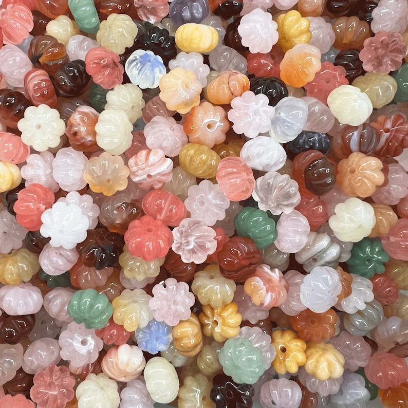 May include: A large assortment of colorful carved gemstone beads in various shapes and sizes. The beads are made of natural stone and have a polished finish.