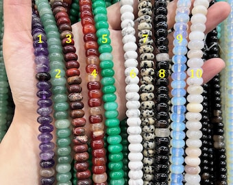 May include: Ten strands of round, flat-disc shaped gemstone beads in various colors and patterns, labeled with yellow numbers 1 through 10. The collection includes purple, green, brown, white, spotted, black, and iridescent white beads.