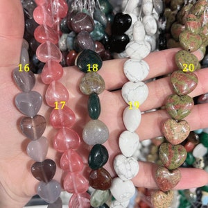 May include: A hand holding strands of heart-shaped beads in various colors and patterns. The beads are labeled 16, 17, 18, 19, and 20.