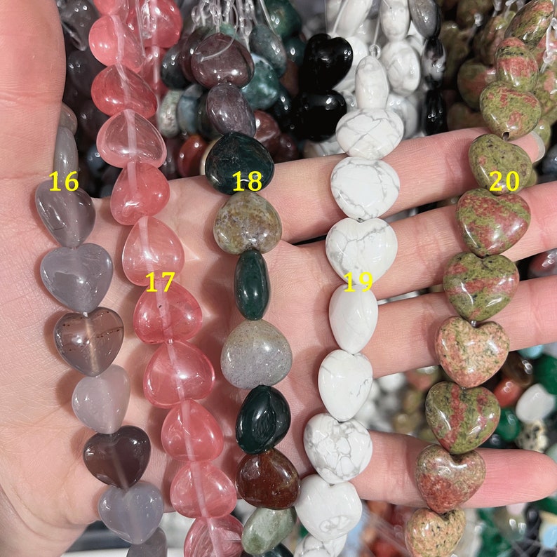 May include: A hand holding strands of heart-shaped beads in various colors and patterns. The beads are labeled 16, 17, 18, 19, and 20.
