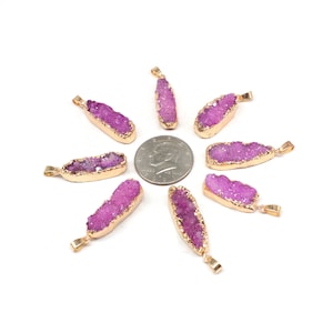 May include: Eight purple and gold druzy crystal pendants arranged in a circle on a white background. The pendants are approximately the size of a US quarter.