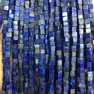 Könnte beinhalten: Eine Strähne dunkelblauer Lapislazuli-Edelsteinkugeln, jede Kugel hat die Form eines quadratischen Würfels.