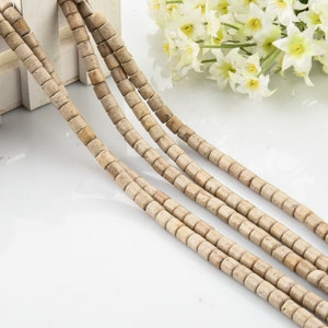 May include: Four strands of beige and brown natural stone beads. The beads are cylindrical and have a smooth, polished finish.