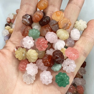 May include: Assortment of colorful gemstone beads in various shades of pink, green, brown, and white. The beads are carved in a flower shape with a hole in the center for stringing.