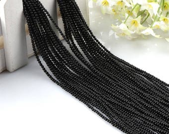 May include: A close-up of a large quantity of black bead strands. The strands are made of small, round beads and are arranged in a neat, parallel pattern.