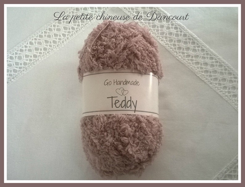 Puede incluir: Un ovillo de hilo suave y esponjoso de color rosa, etiquetado como "Go Handmade Teddy".