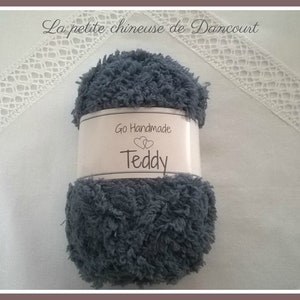Puede incluir: Un ovillo de hilo gris con la etiqueta "Go Handmade Teddy" para tejer o hacer ganchillo.