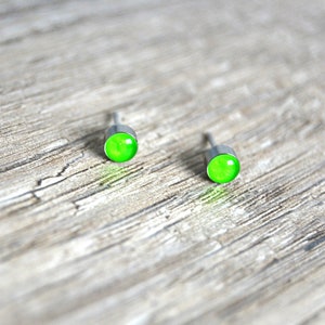 Może przedstawiać: Para srebrnych kolczyków z jasnozielonymi okrągłymi kamieniami.