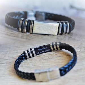 May include: Black leather bracelet with a silver metal clasp and a silver metal plate engraved with the text "Sevalex 12 avril 2003".