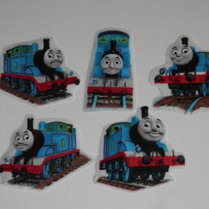 May include: Five fabric patches featuring the blue steam locomotive character Thomas the Tank Engine. Each patch displays the train from different angles, including side and front views, with red accents on the wheels and buffers on a track.
