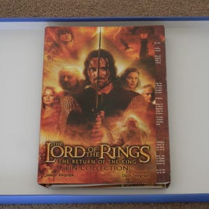 May include: A rectangular box set titled The Lord of the Rings The Return of the King Pin Collection. The cover features a collage of characters, a sword, and a tower in warm orange and brown tones. The text Sunday Telegraph and Daily Telegraph appears.