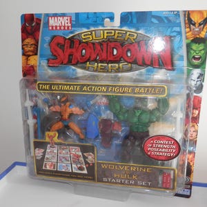 May include: A Marvel Heroes Super Showdown Wolverine vs. Hulk starter set action figure pack in original packaging. The blister card features graphics of various Marvel characters and includes two action figures, a game board, and red dice.