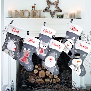Op de afbeelding: Zes grijze en witte kerstsokken met verschillende geborduurde dierenontwerpen en gepersonaliseerde namen: Papa, Max, Amelia, Freddy, Mama en Opa.