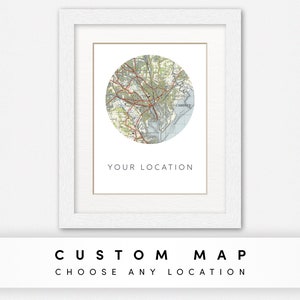 May include: A white framed print featuring a circular map of a city in a light green, brown, and blue colour scheme. The text "YOUR LOCATION" is printed below the map.