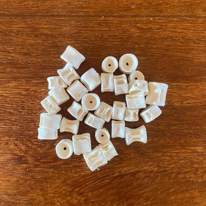 Può includere: Una collezione di piastrelle in ceramica bianca di diverse forme e dimensioni. Le piastrelle hanno una finitura liscia e opaca e sono disposte in un motivo casuale.