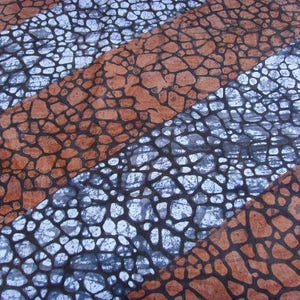 Könnte beinhalten: Ein Stoff mit einem sich wiederholenden Muster aus braunen und silbernen geometrischen Formen. Die Formen ähneln kleinen Steinen oder Kieselsteinen.