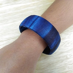 Könnte beinhalten: Ein blaues und schwarzes Holz-Armband mit Marmorierung.