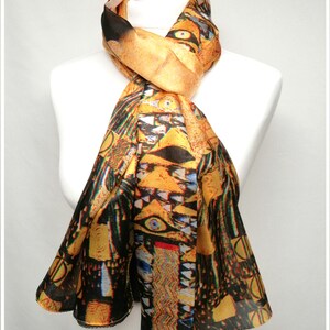 May include: A yellow, black, and green silk scarf with a colorful abstract design. The design features geometric shapes and a repeating pattern of eyes.